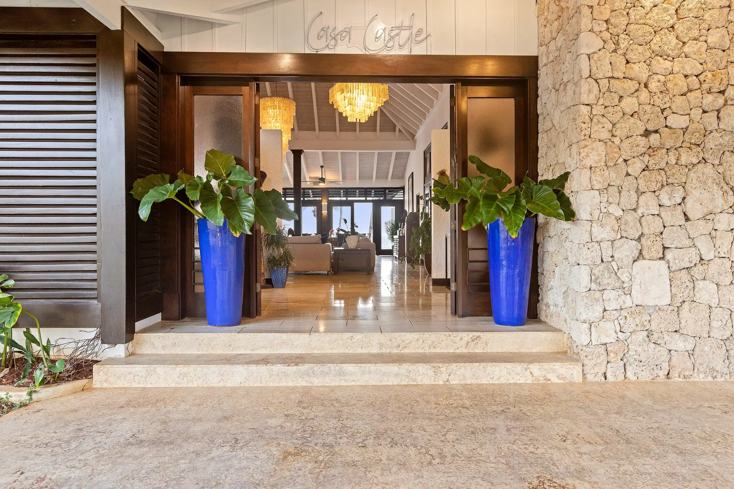 The arrival courtyard at Costa Verde 3, coral stone walls and tall blue urns flanking the entrance