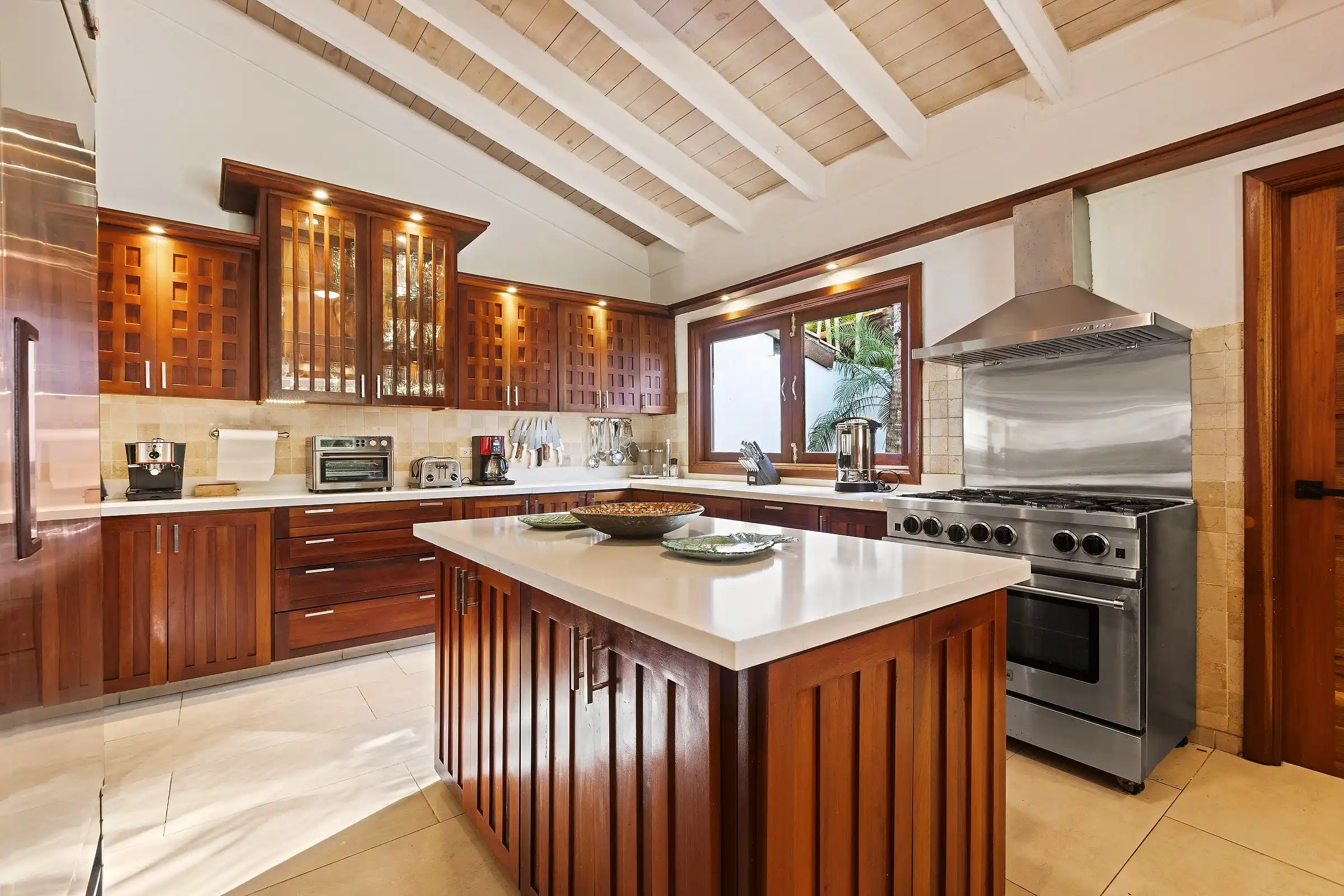 The chef's kitchen at Costa Verde 3 in rich tropical hardwood, with a professional range and a large prep island
