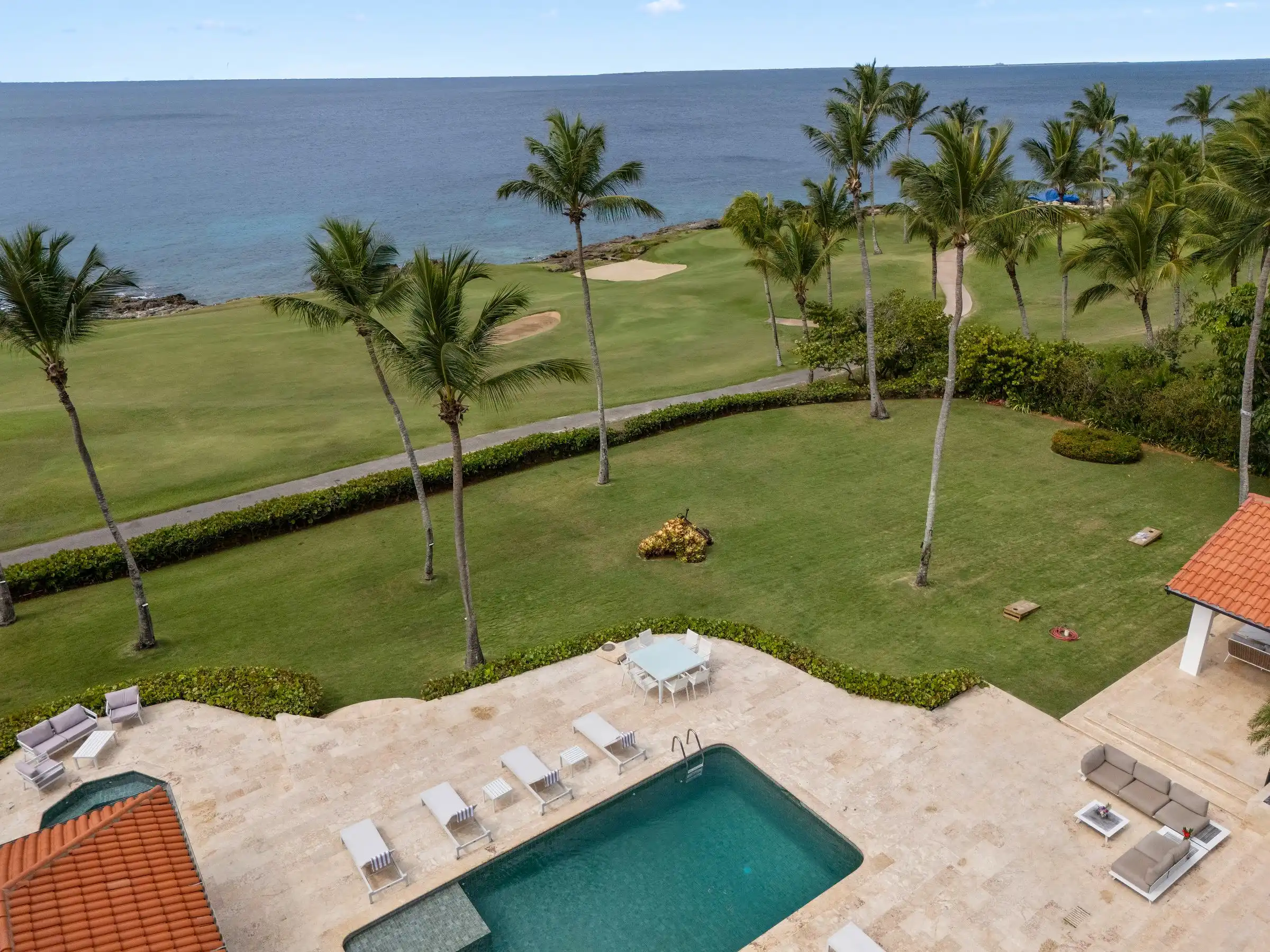 Aerial view of Costa Verde 3 — the ocean-front pool, lawns and palms of the villa on the 8th hole of Teeth of the Dog, Casa de Campo