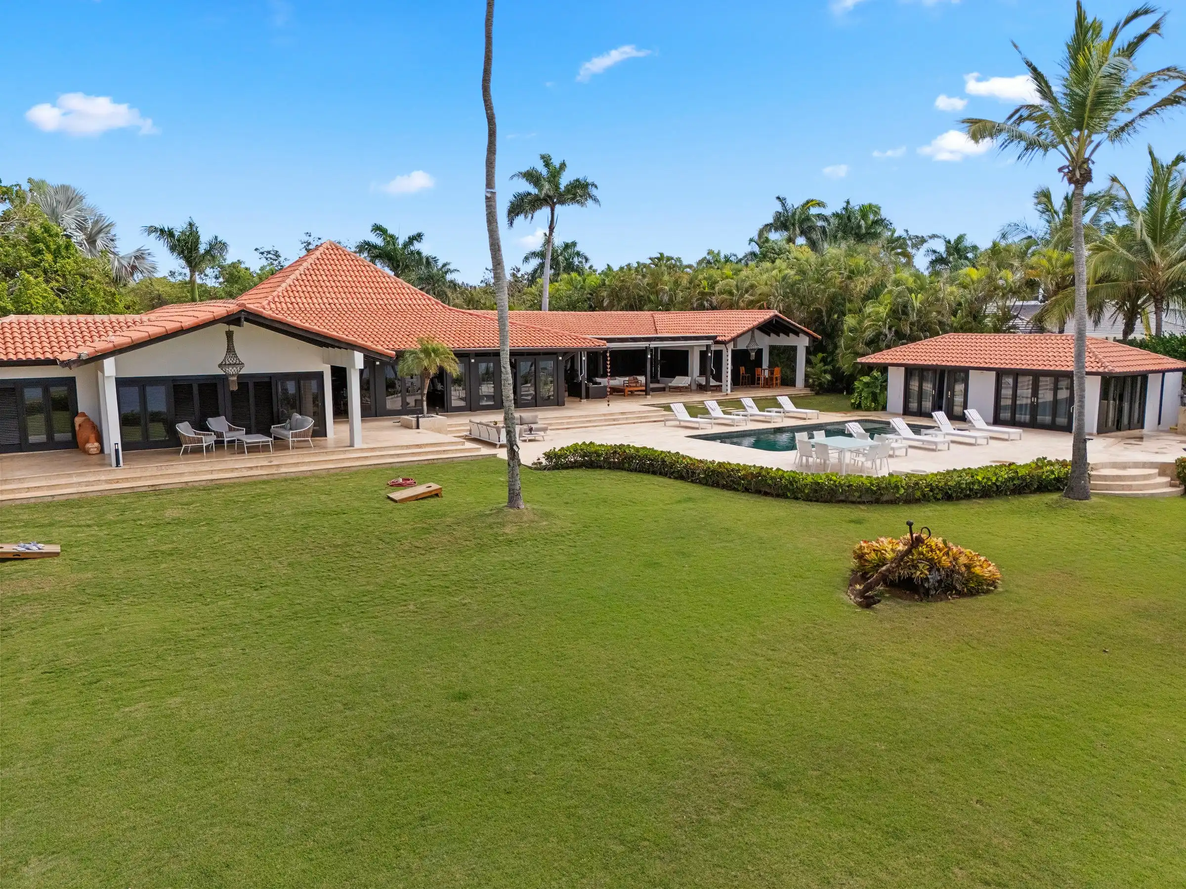 Low aerial of the full ocean-facing elevation of Costa Verde 3 across its lawn, La Romana, Dominican Republic