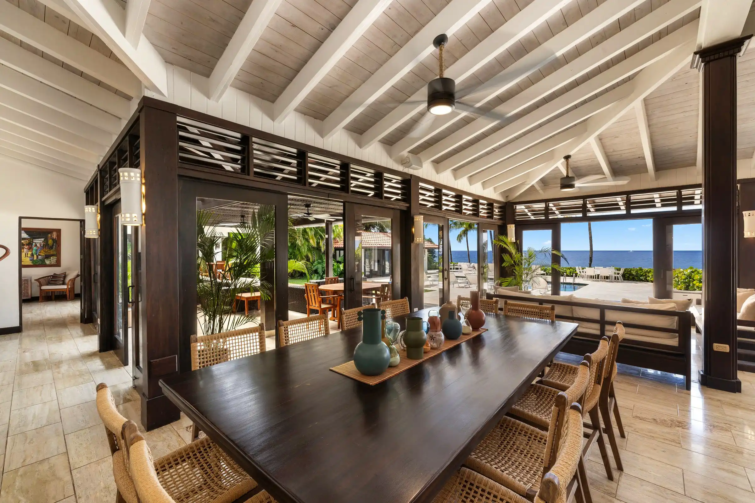 The dining table at Costa Verde 3 set beneath the beamed roof, with the Caribbean framed at the end of the room