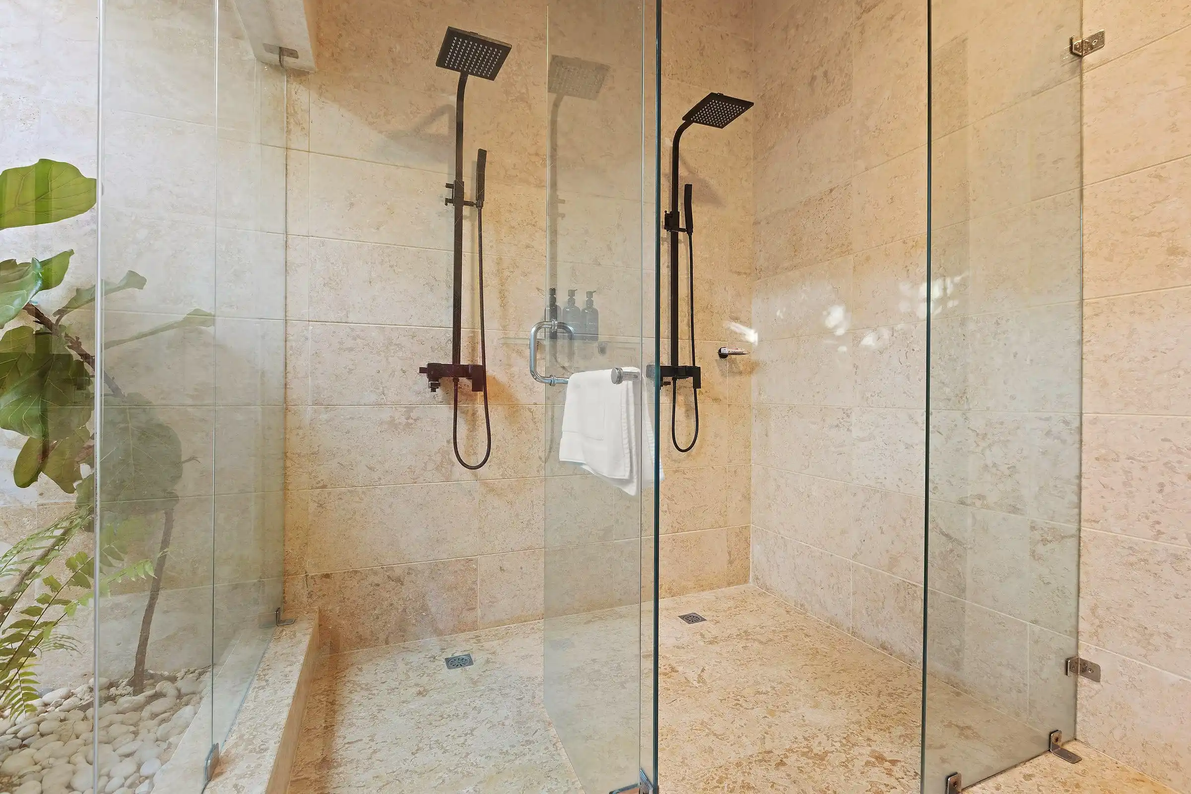 Double walk-in shower at Costa Verde 3 in coral stone, open to a planted courtyard