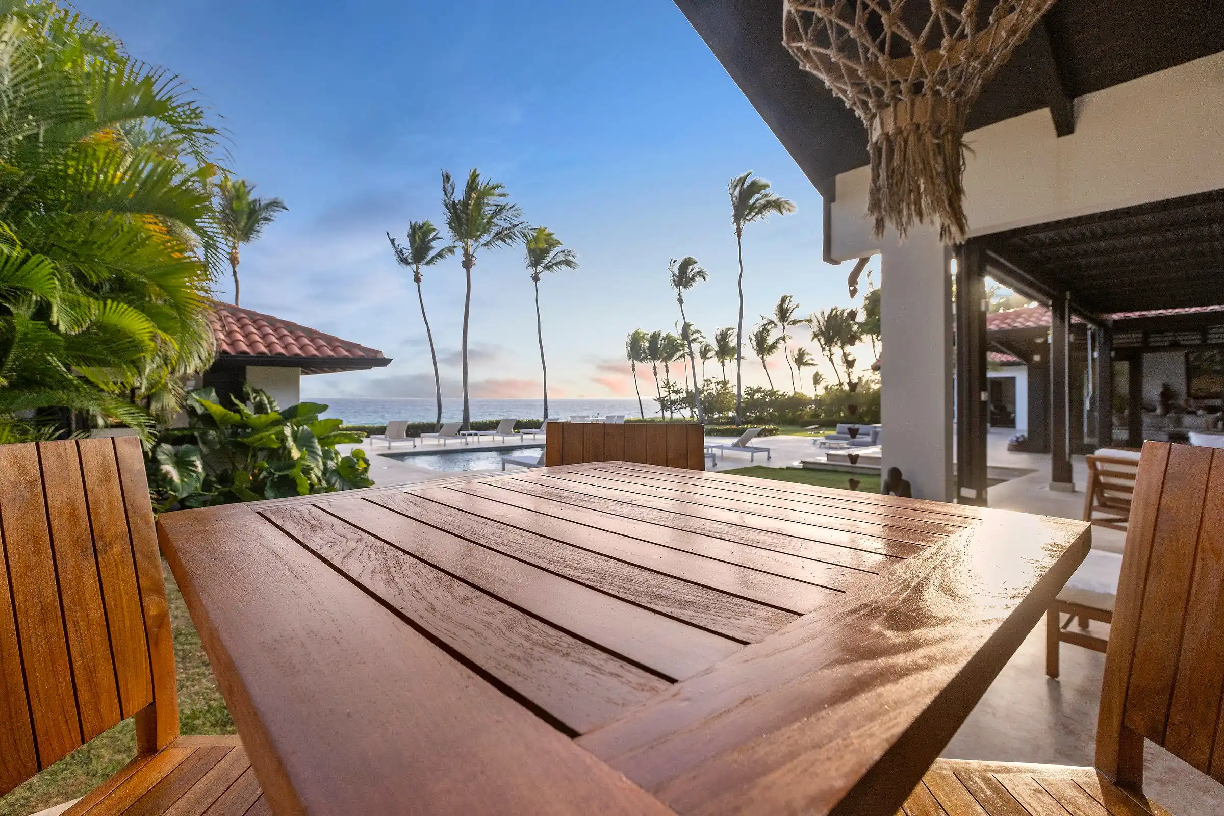 Hardwood dining table on the poolside terrace at Costa Verde 3 in low evening light