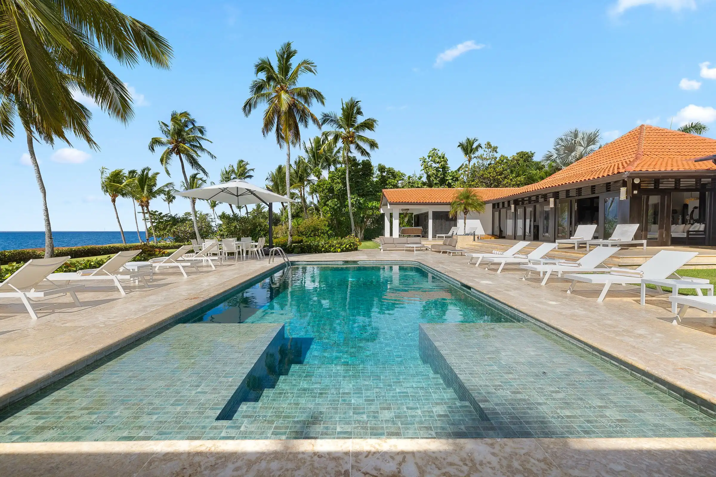 The long lap pool at Costa Verde 3 with loungers, palms and the open Caribbean beyond