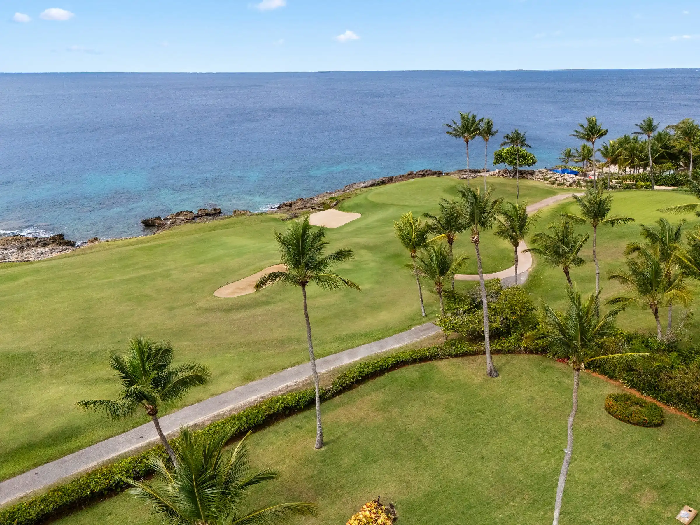 Aerial looking out over manicured fairway, palms and the rocky ocean edge below Costa Verde 3 in Casa de Campo, Dominican Republic