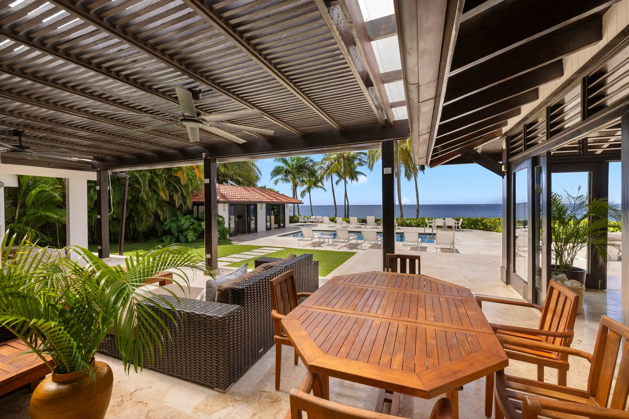 Outdoor dining table and chairs on the covered terrace at Costa Verde 3, gardens and pool beyond