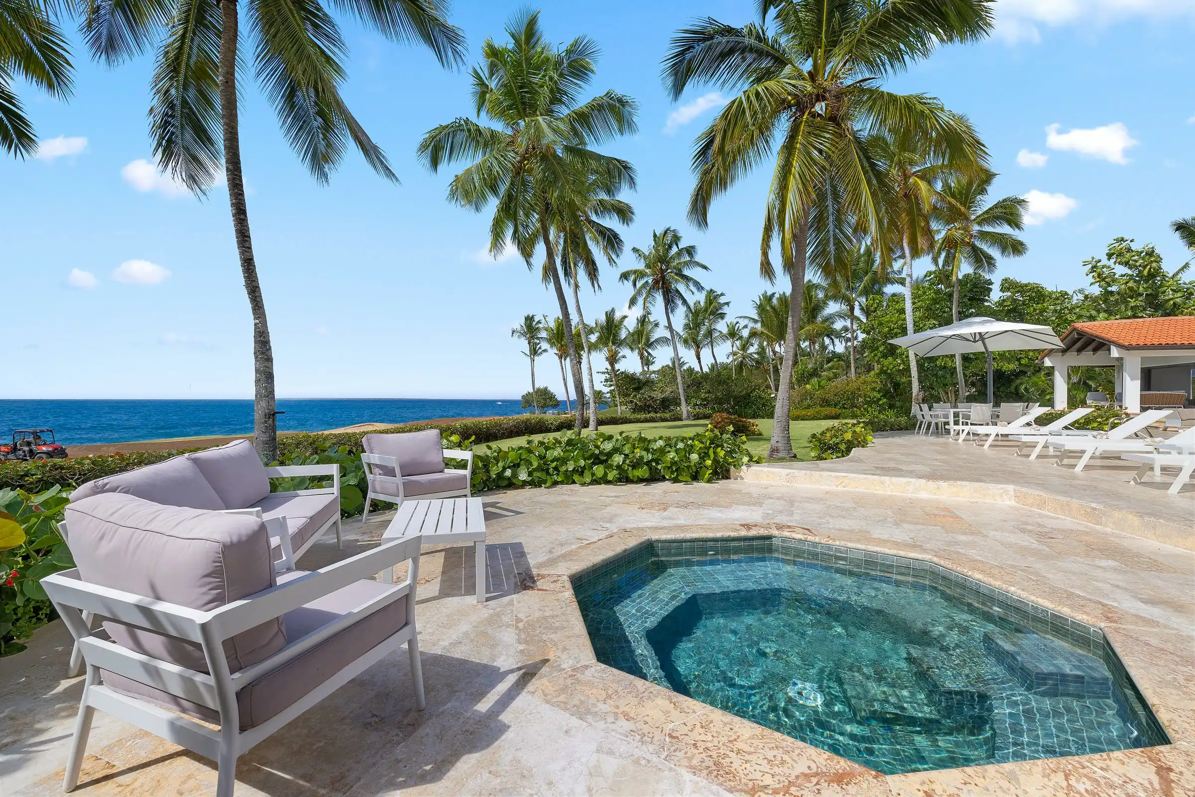 The circular plunge pool and seating area at Costa Verde 3, shaded by palms with the Caribbean beyond