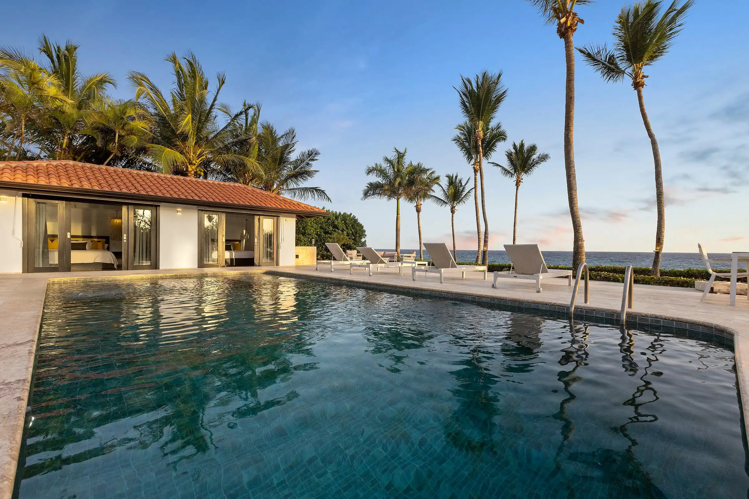 Dusk over the pool terrace and poolhouse at Costa Verde 3, palms leaning over the water