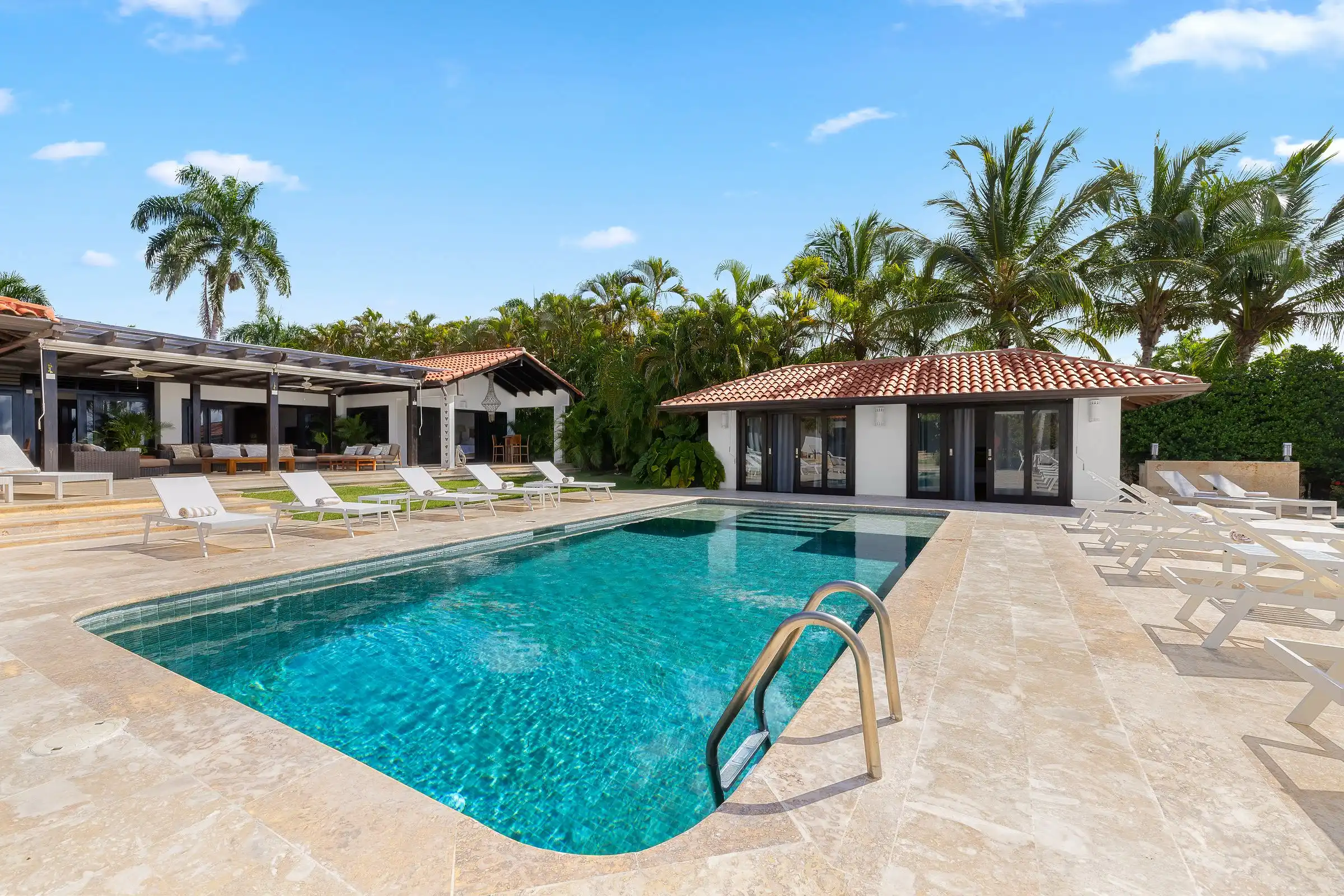Wide view of the pool terrace at Costa Verde 3, with loungers set between the villa and the poolhouse