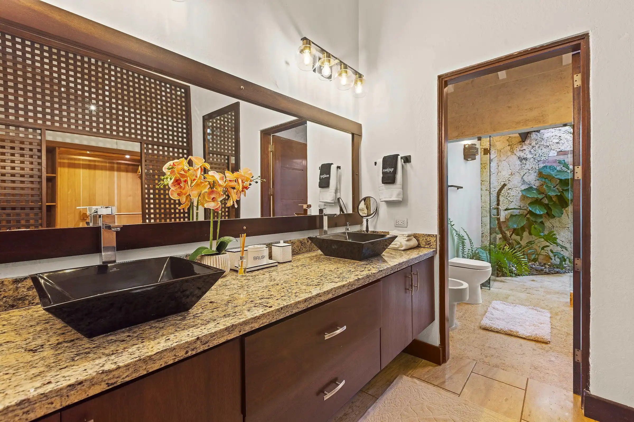 Spa bathroom at Costa Verde 3 with stone vessel basins, granite counters and a planted garden view