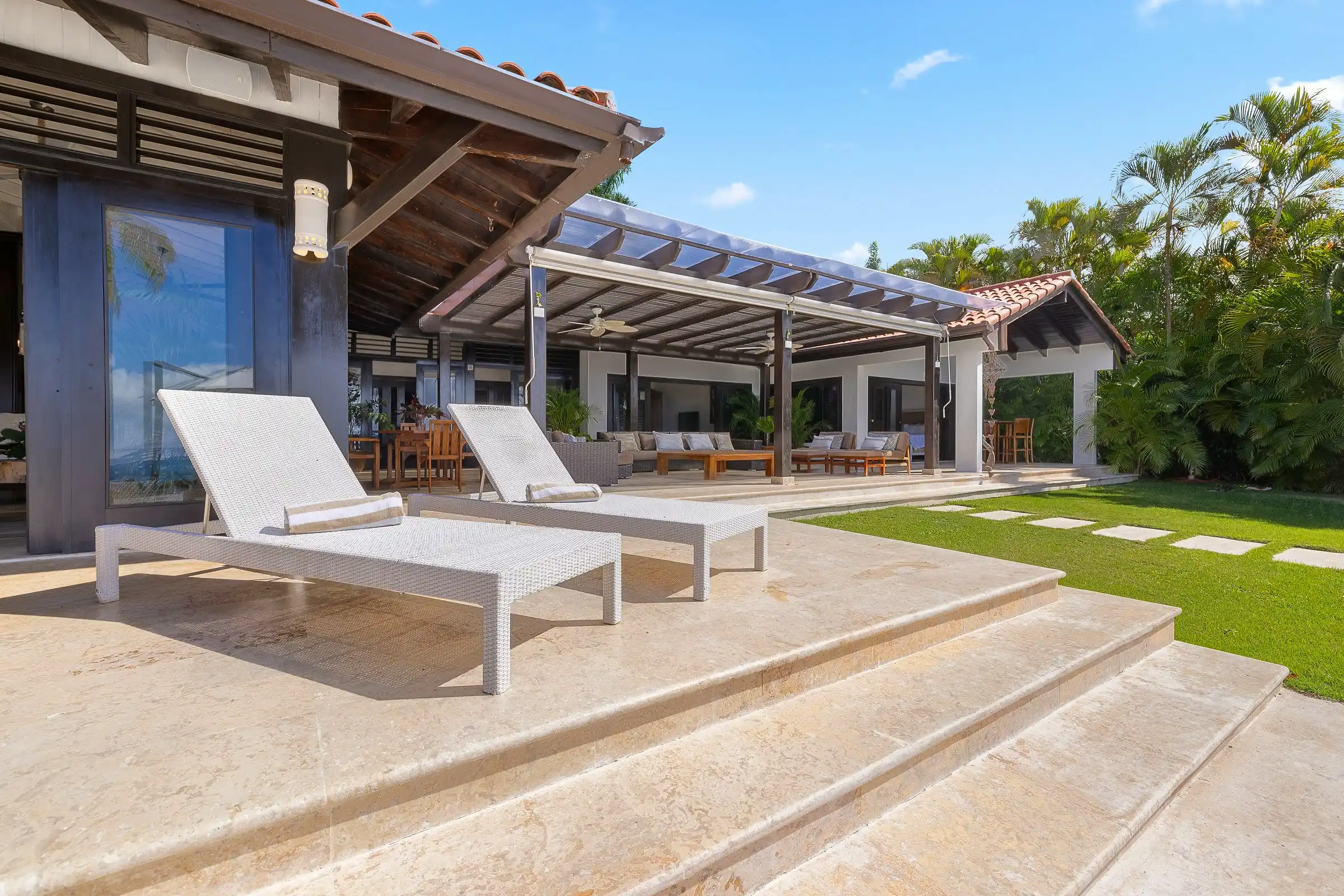 Loungers on the stone sun terrace at Costa Verde 3, lawn and covered pavilions behind