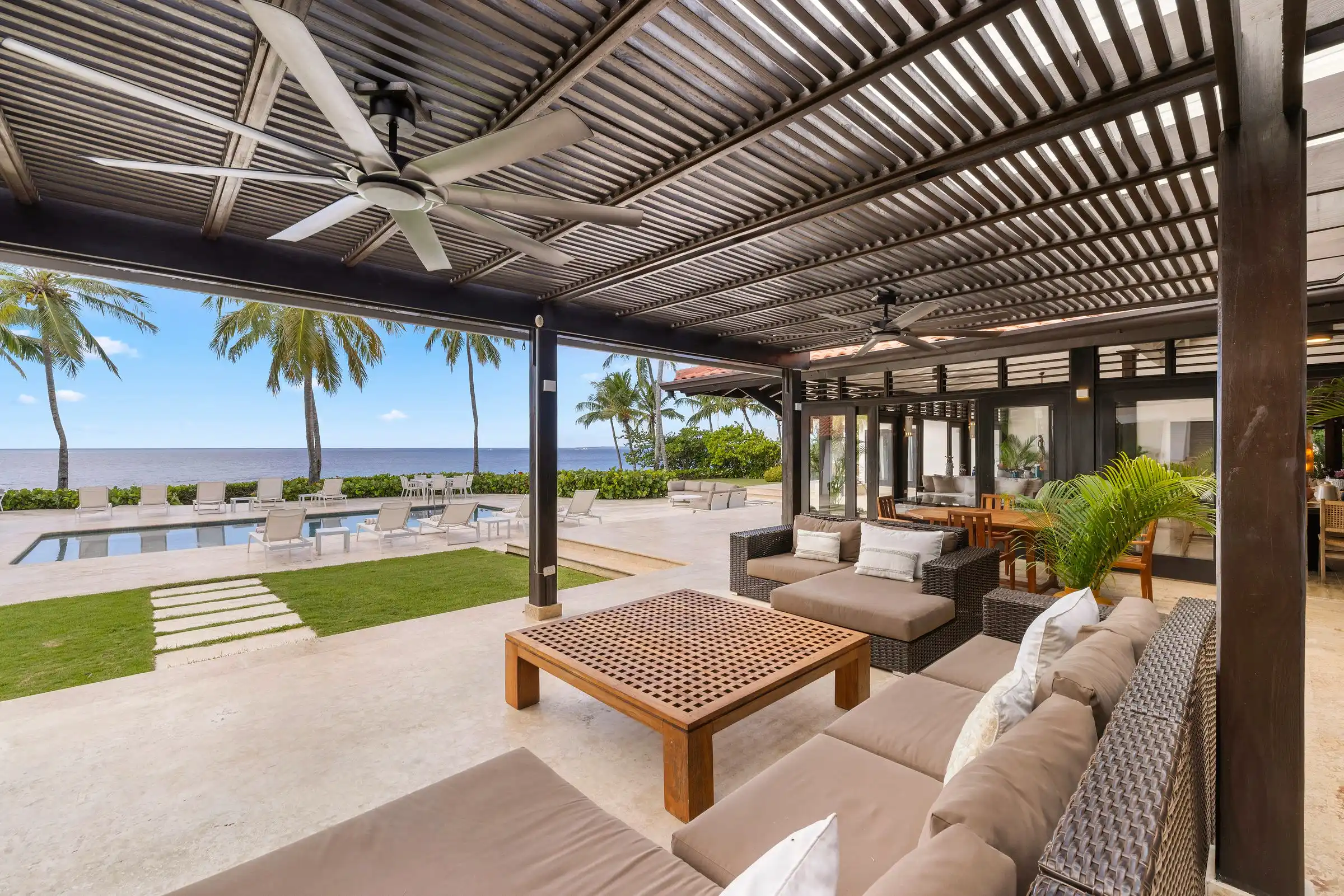 Terrace lounge at Costa Verde 3 with the pool, lawn and Caribbean framed between timber columns