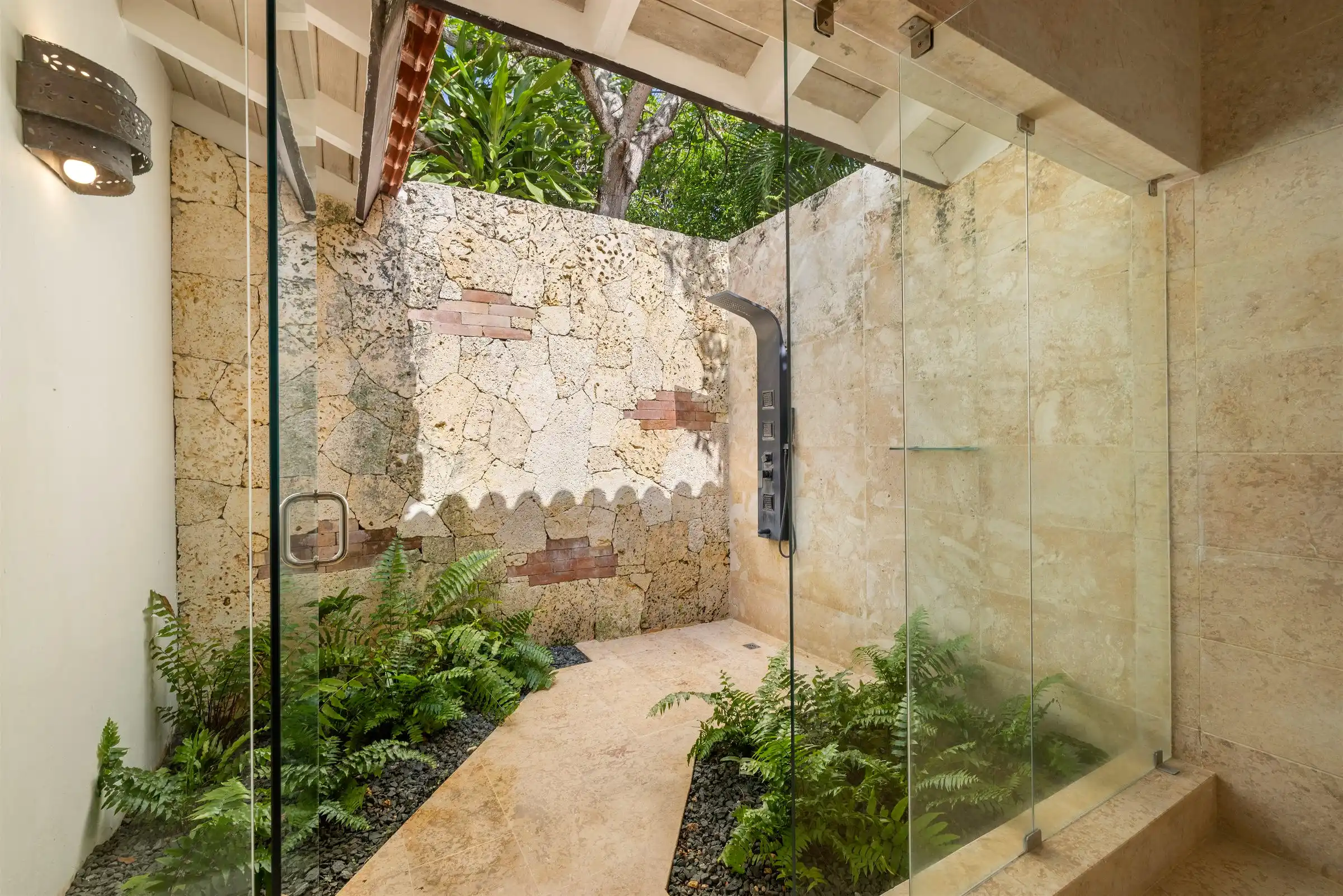 Tropical outdoor garden shower at Costa Verde 3, enclosed by coral stone walls and planting