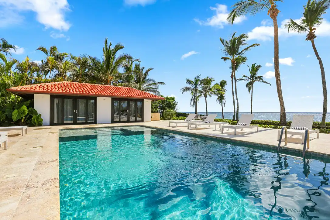 Turquoise water of the villa pool with the poolhouse and palms beyond, Casa de Campo