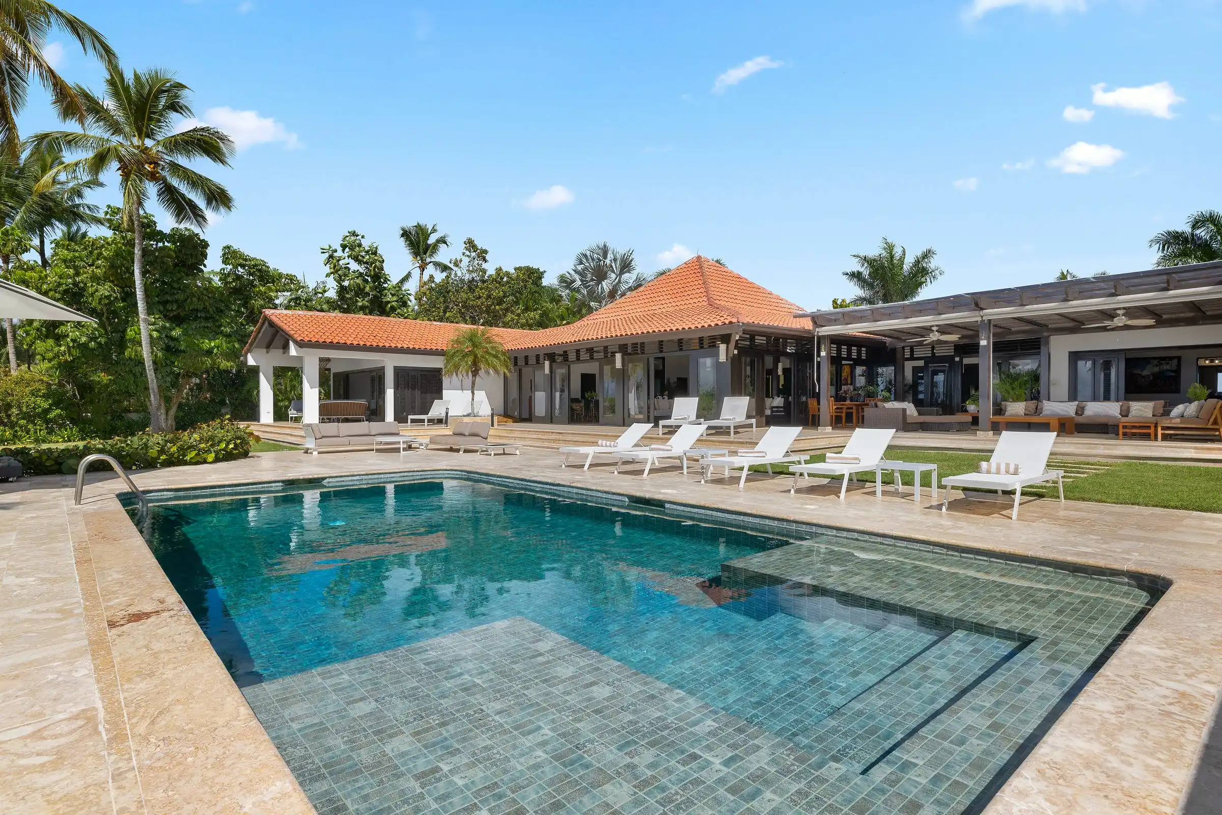The villa's covered terraces seen across the pool and lawn at Costa Verde 3, La Romana