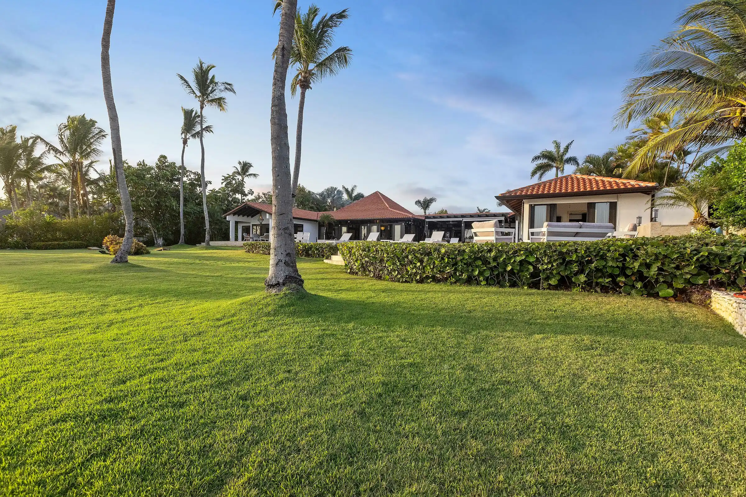 Costa Verde 3 seen from across its lawn at golden hour, palms rising above the tiled roofline
